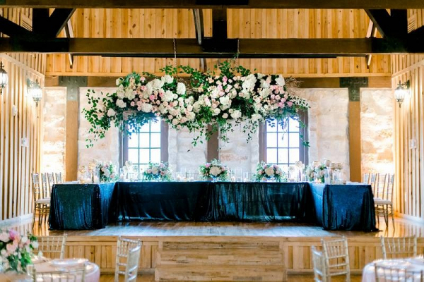 Head table at wedding with giant floral chandelier 