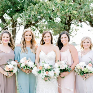 Bridesmaids in mismatched pink, peach, and blue dresses
