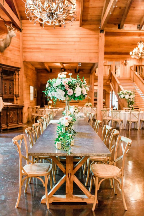 Lodge wedding reception with tall pink and white floral centerpieces
