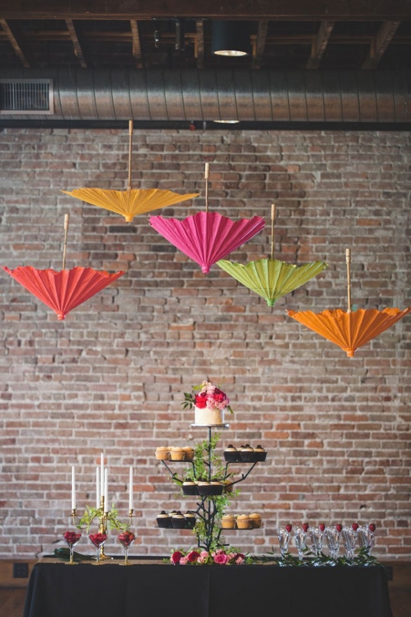 A whimsical dessert display with a cupcake tower and hanging parasols