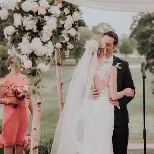 Outdoor wedding ceremony with floral and draping chuppah