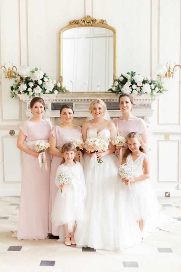 elegant bride with her bridesmaids in pale pink dresses and flower girls