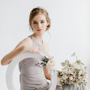 bridesmaid seated on a white chair holding a bouquet of flowers