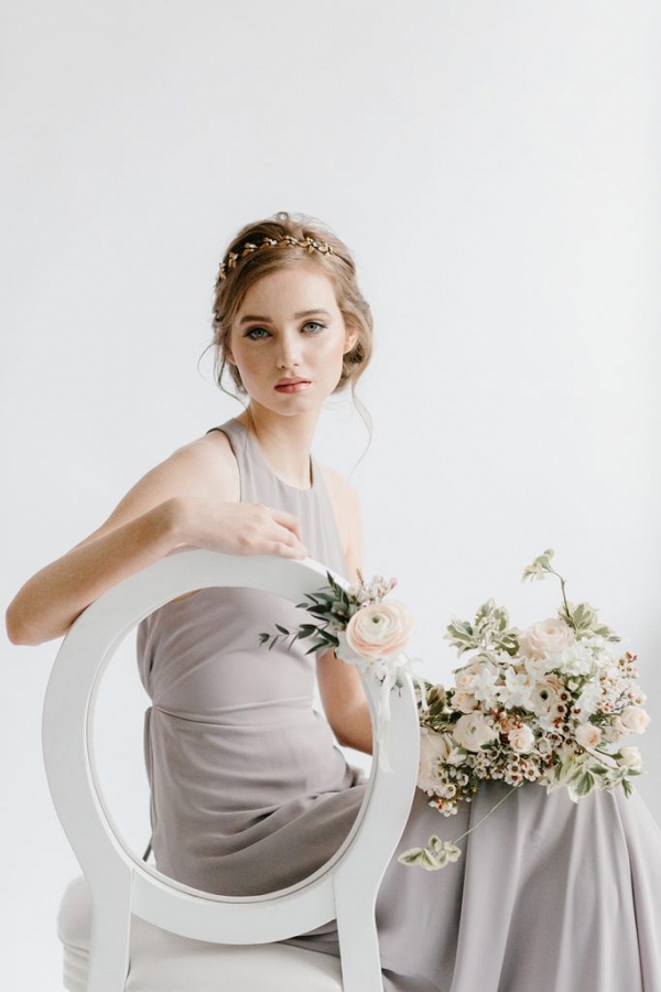 bridesmaid seated on a white chair holding a bouquet of flowers