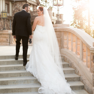 bride and groom portrait on mansion steps with wedding dress train flowing