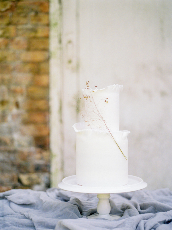 The beautiful fine art wedding cake by Yolk decorated with a spring of golden grass
