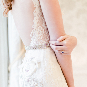 Dramatic low back lace wedding dress with beaded belt and sapphire engagement ring