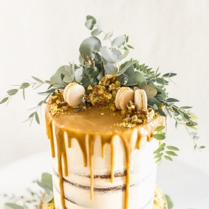 wedding cake topped with foliage and macarons
