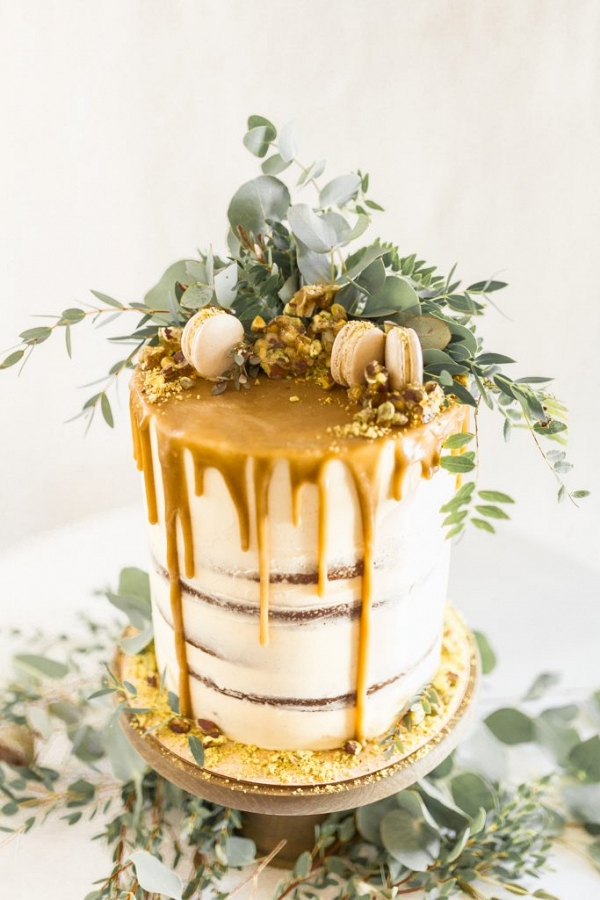 wedding cake topped with foliage and macarons