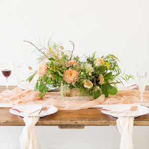 Rustic chic table setting with a fine art twist and peach colour palette floral centrepiece linen napkins and red wine