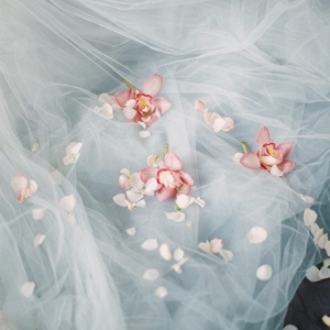 scattering petals and orchids upon the tulle wedding dress