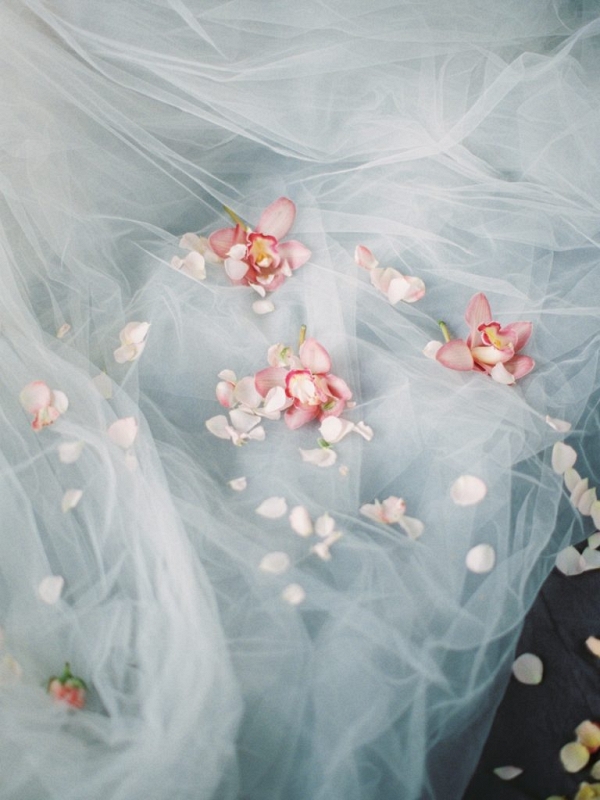 scattering petals and orchids upon the tulle wedding dress