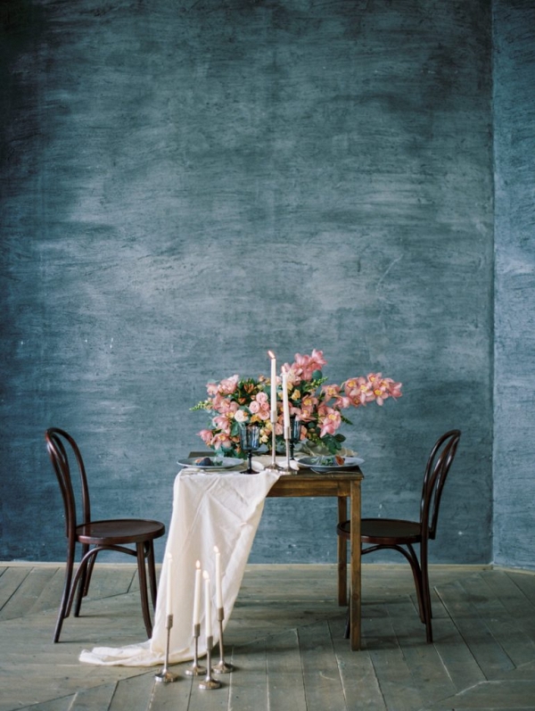 table setting against blue backdrop and decorated with pink orchid flowers