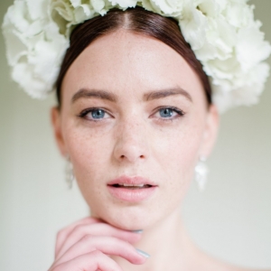 Bride wearing a classic white hydrangea crown with pearl drop earrings and something blue nail polishe