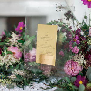 Elegant statement wedding menu design in gold displayed in the floral runner