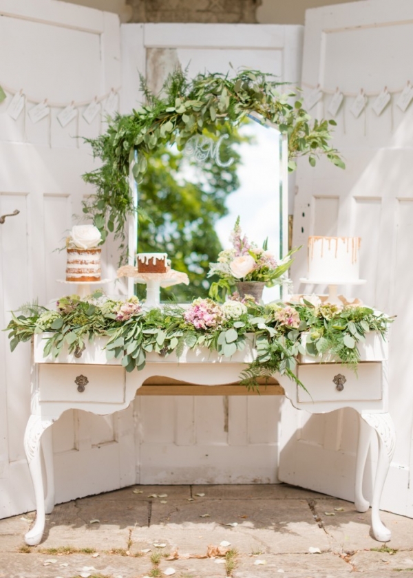Rustic cake display with naked cakes and organic foliage on a vintage dresser