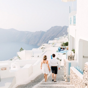 couple walking hand in hand along the quaint streets of Santorini