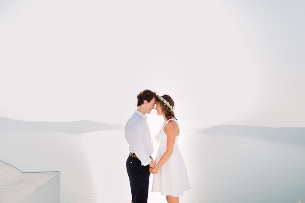 couple stand together with the background of the ocean surrounding  Santorini 