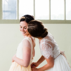 Classic bride in a yellow wedding dress with bridesmaid in white lace detailed dress