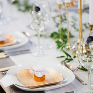 Urban organic wedding tables with a delicate jasmine floral runner, gold candlesticks and DIY honey pot favours 