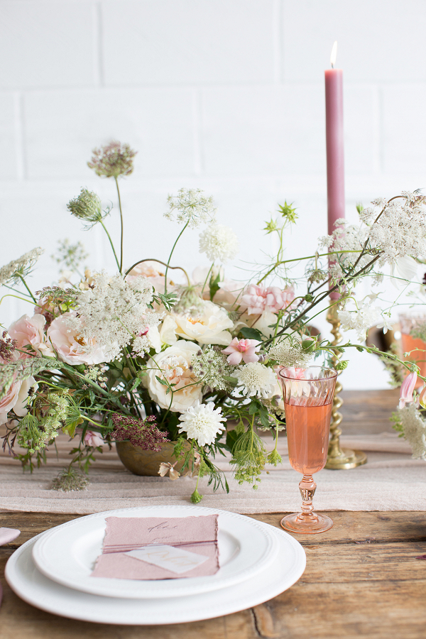 Blush pink table setting with a rustic fine art feel centrepiece of flowers stationery and candles
