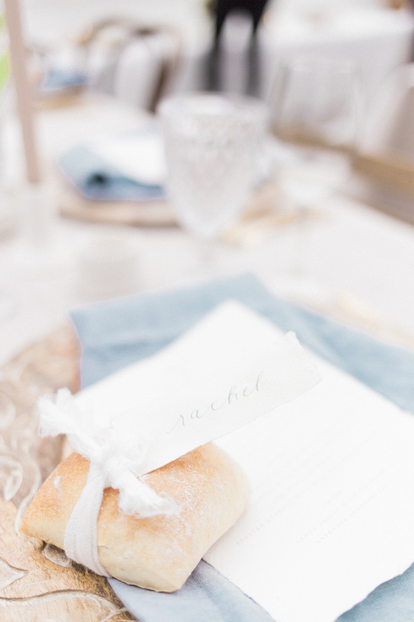 Delicate calligraphy place cards tied with silk ribbon to bread rolls for the place setting