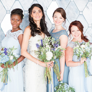 bride in lace wedding dress and bridesmaids in blue lace dresses with blue and white bouquets