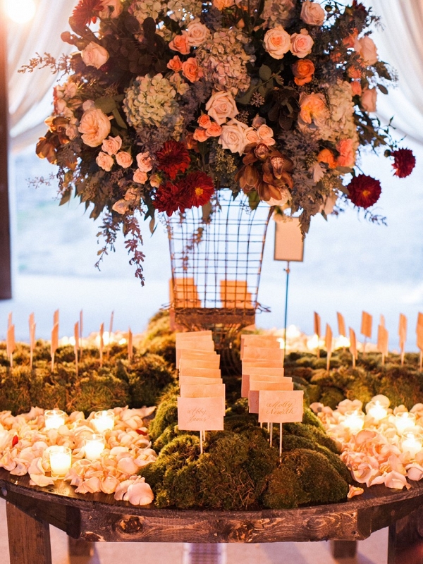 Romantic Candlelight, Fresh Moss, Rose Petals, and a Lush Elevated Floral Arrangement Decorate This Escort Card Display