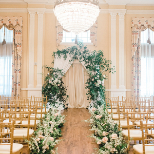 Elegant ballroom ceremony with floral arch and aisle