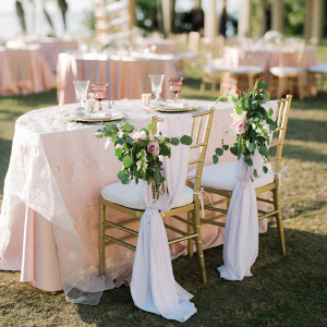 Sweetheart table with blush linens and greenery chair florals