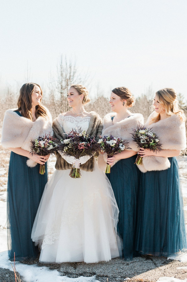 Winter bridesmaids in long tulle teal gowns and fur stoles