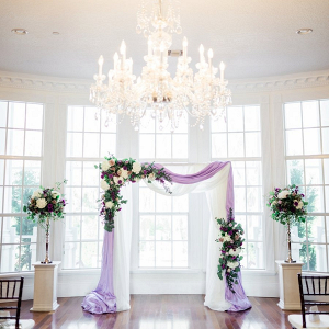 Purple and cream draped ceremony arch