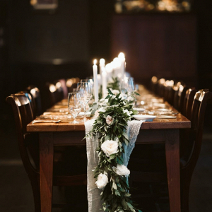 Farm table reception with greenery runner and candles