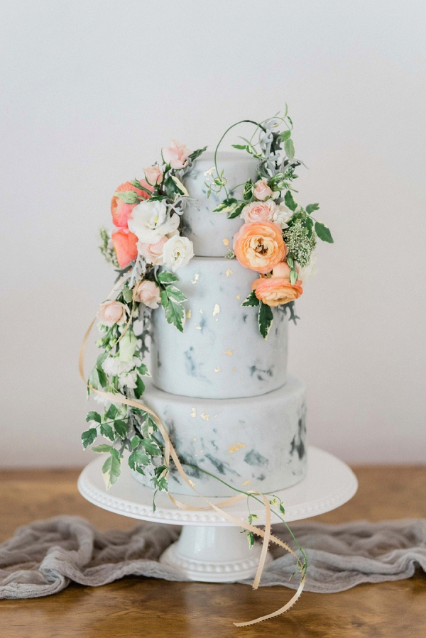 Gray painted wedding cake with gold leaf and fresh florals
