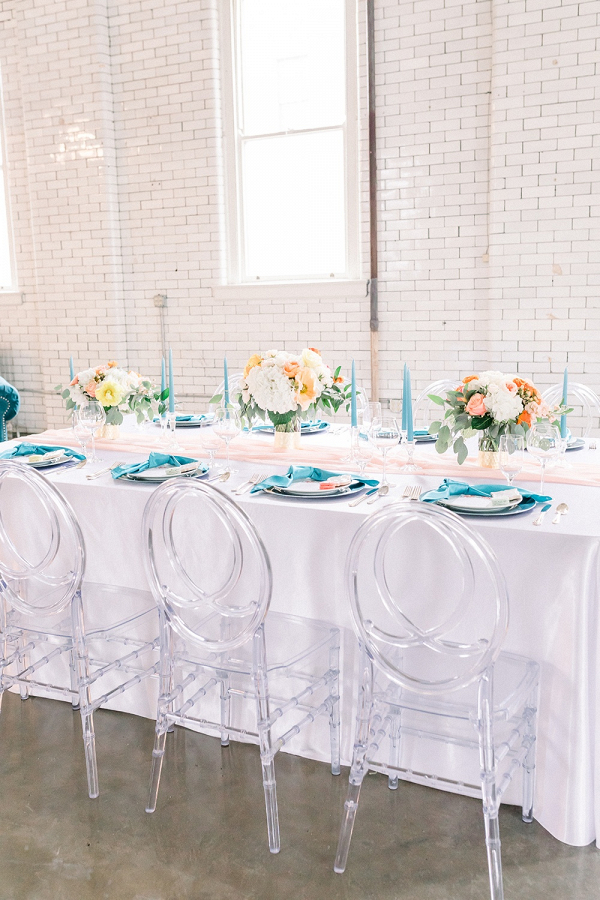 Coral and teal wedding table with clear chairs