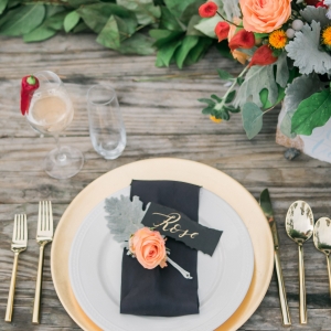 Gold rimmed plates and gold flatware with black and peach details 