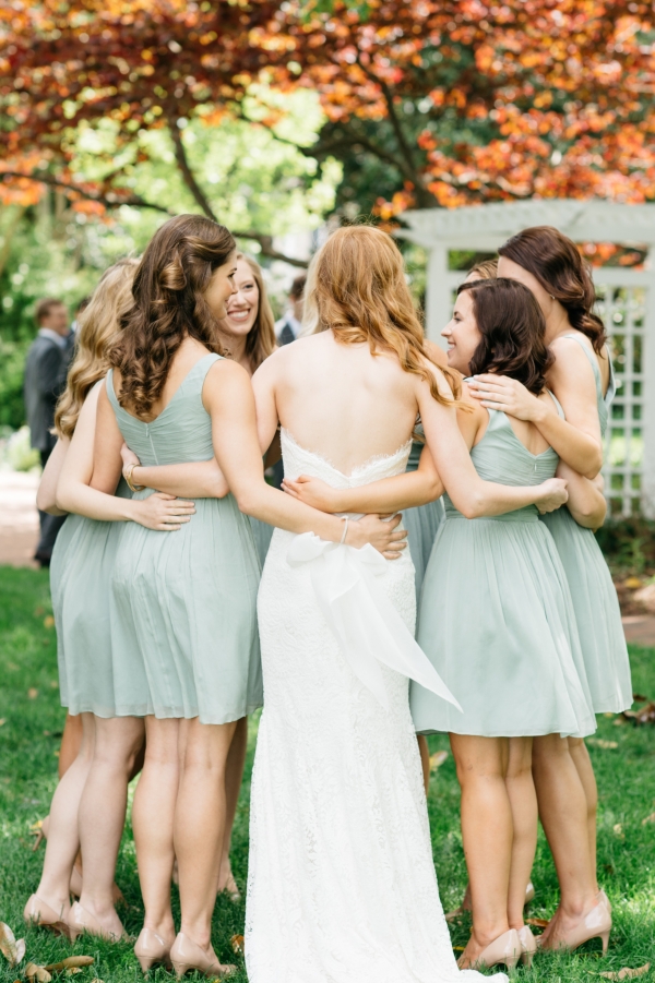 Bride with bridesmaids in mint dresses hugging 