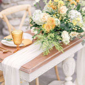 stunning tablescape with a white cheesecloth and mustard colored goblets and florals