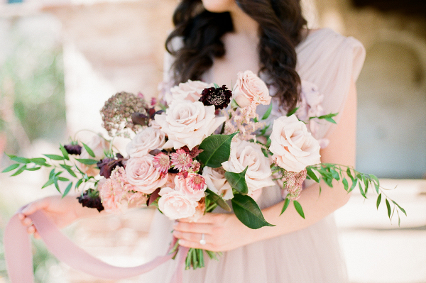 Bride with beautiful long brown hair holding a mauve bouquet