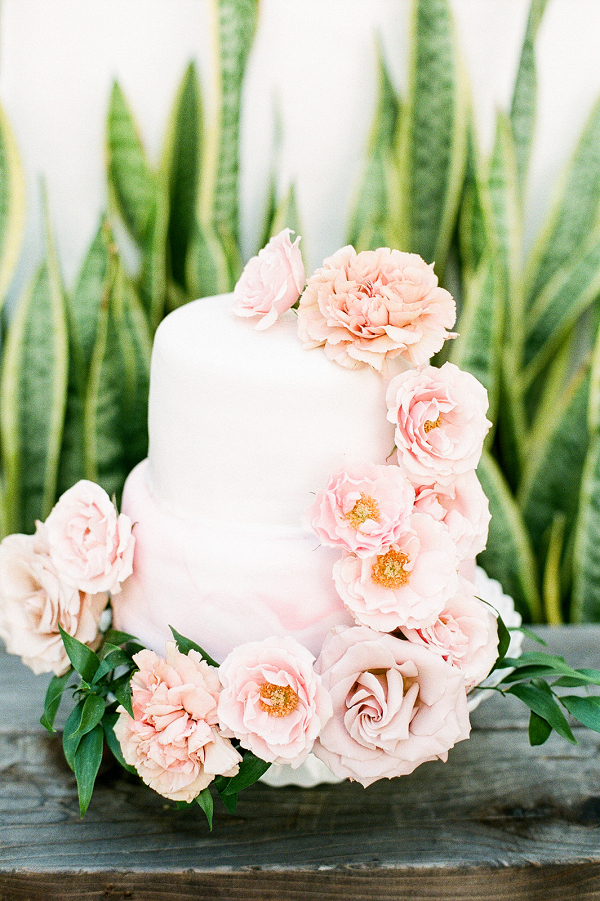 White two tier cake with pink cascading roses