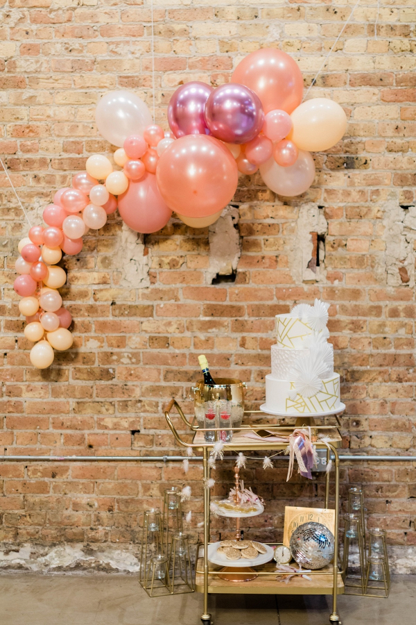 Modern white and gold wedding cake with balloon garland backdrop