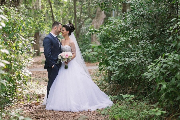 Bride in Strapless Wedding Ball Gown & Groom Wedding Portrait with Lush Greenery Backdrop