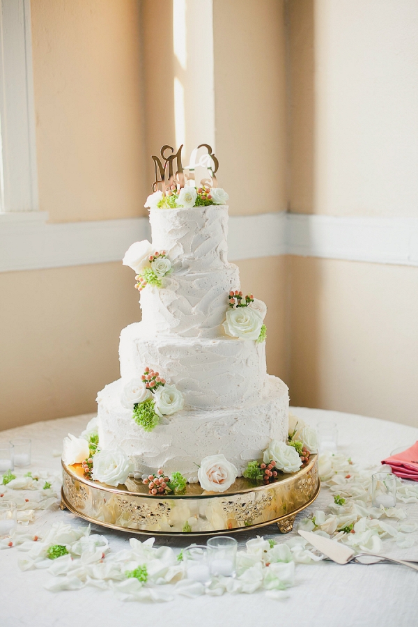 Wedding Reception 4-Tiered White Wedding Cake with Gold Initial Monogram Cake Topper and White Rose and Green Floral Accent