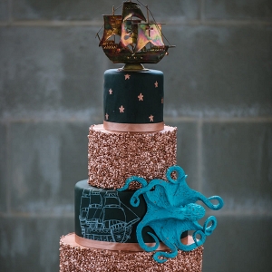 Black and Gold Glitter 5-Tiered Nautical Inspired Wedding Cake with Pirate Ship Cake Topper and Octopus Details 