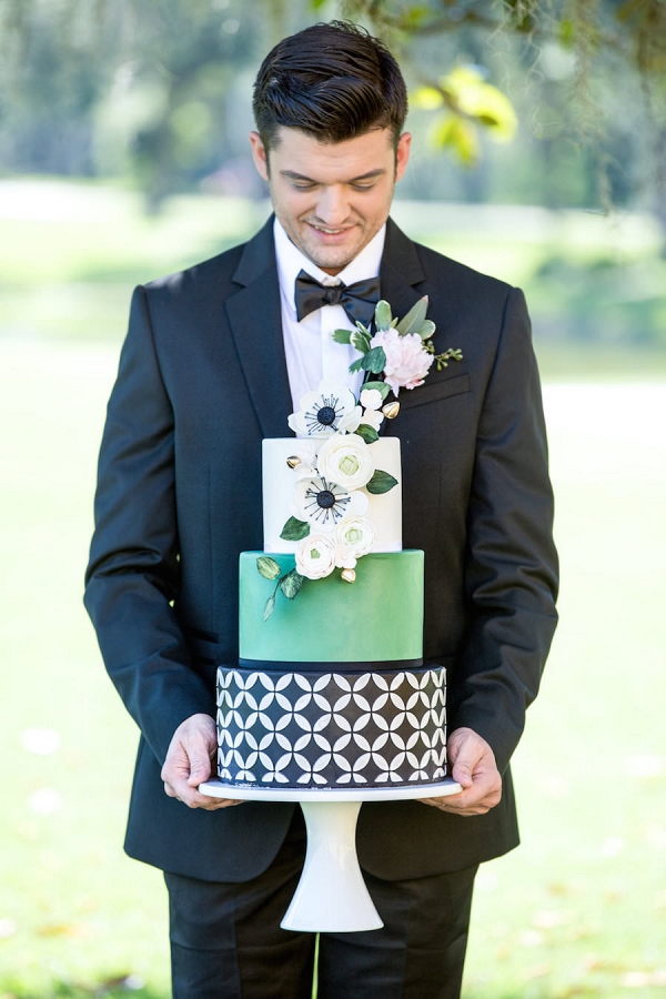 Groom Holding Green, Black and Silver Modern Geometric Wedding Cake with Sugar Flowers