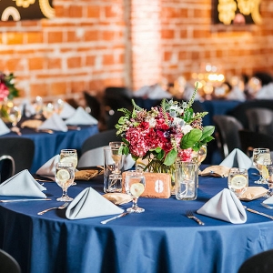 Merlot Red and White Wedding Centerpieces with Greenery and Blue Linen with Brick Venue Walls