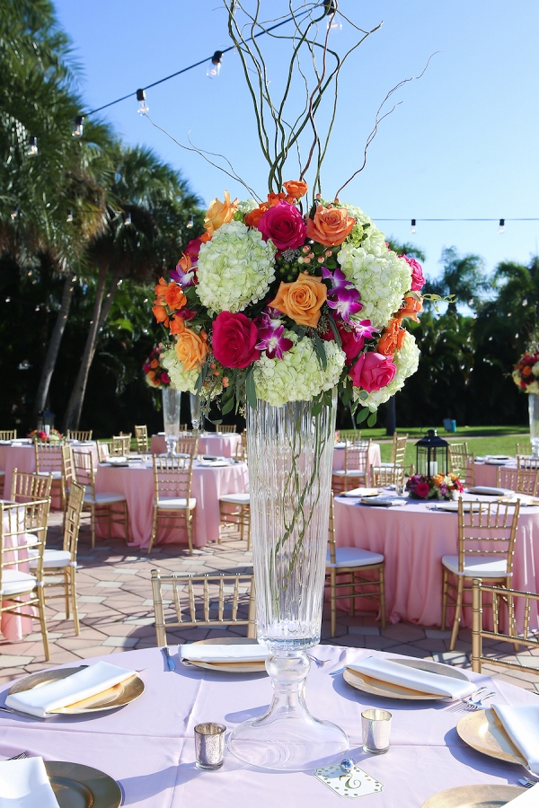 Outdoor Wedding Reception Décor with Gold Chiavari Chairs, Pink Linens and Orange, Bright Pink and Fuchsia Floral Centerpieces with Lanterns and Market Twinkle Lights 