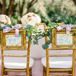 Outdoor Wedding Reception Seating with Watercolor Bride and Groom Chair Signs with Greenery with Gold Chiavari Chairs 