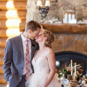 Couple kisses in front of a fireplace at a ski lodge