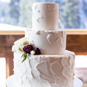 simple butter cream wedding cake with 3 tiers and burgundy and ivory ranunculus
